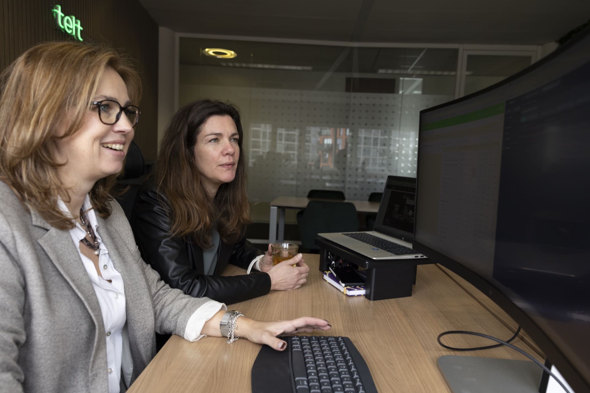 Twee collega's van telt® werken samen achter een beeldscherm op het kantoor in Hoofddorp