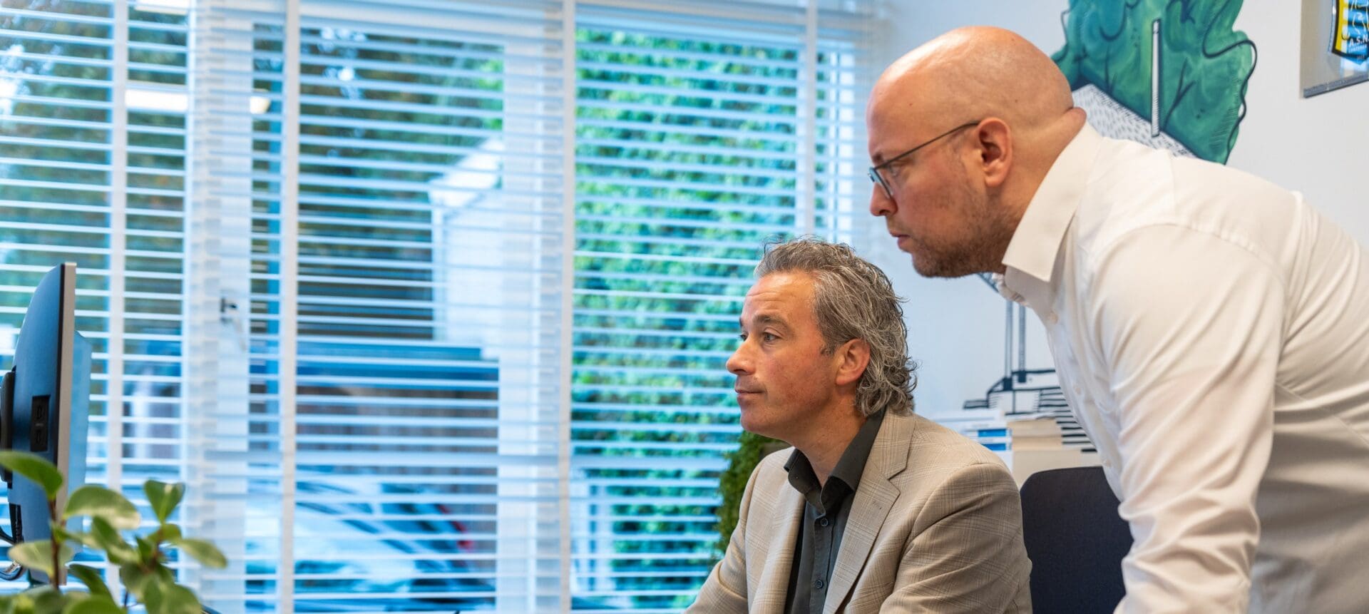 Twee collega's van telt bekijken samen een scherm op kantoor